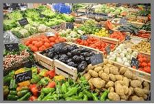 Fresh organic vegetables in colorful display bins with wooden crates at St Charles Plastic Surgery's summer market event.