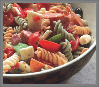 Rotini pasta salad with tomatoes, peppers, olives, and cheese in a bowl, showcasing a fresh meal option.